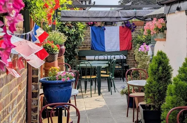 Cafe St Pierre’s courtyard garden with flowers, café chairs and a French flag.